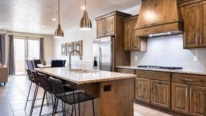 Een moderne keuken met houten kastjes, een roestvrijstalen koelkast en een groot eiland met barstoelen.