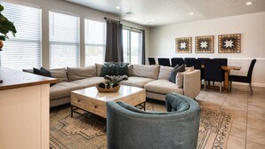 Een moderne woonkamer met een zithoek, een salontafel en een eethoek met stoelen en een tafel.