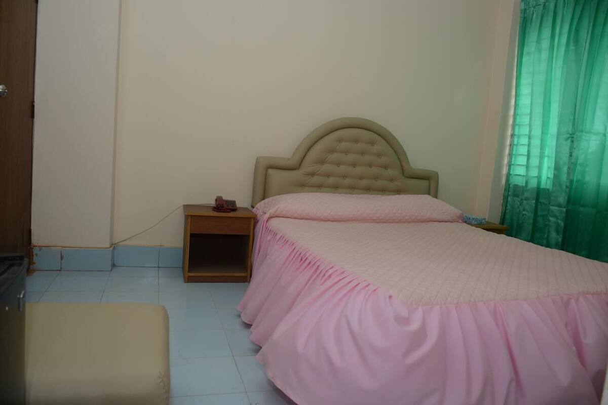 A bedroom with a bed, a nightstand, and a small table.