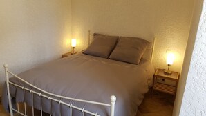 Un lit simple avec un cadre en métal, deux tables de chevet avec des lampes et un mur à texture.