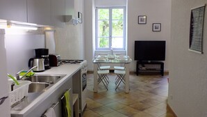 Une cuisine compacte avec un coin repas, une fenêtre et un téléviseur à écran plat.