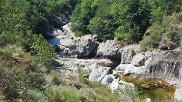 Un paysage rocheux avec une rivière, une végétation luxuriante et une petite cascade.