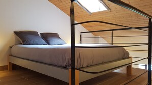 Una cama litera con dos almohadas, un tragaluz y suelo de madera.