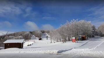 Paisaje nevado con una pista de esquí, un edificio pequeño y un cartel.