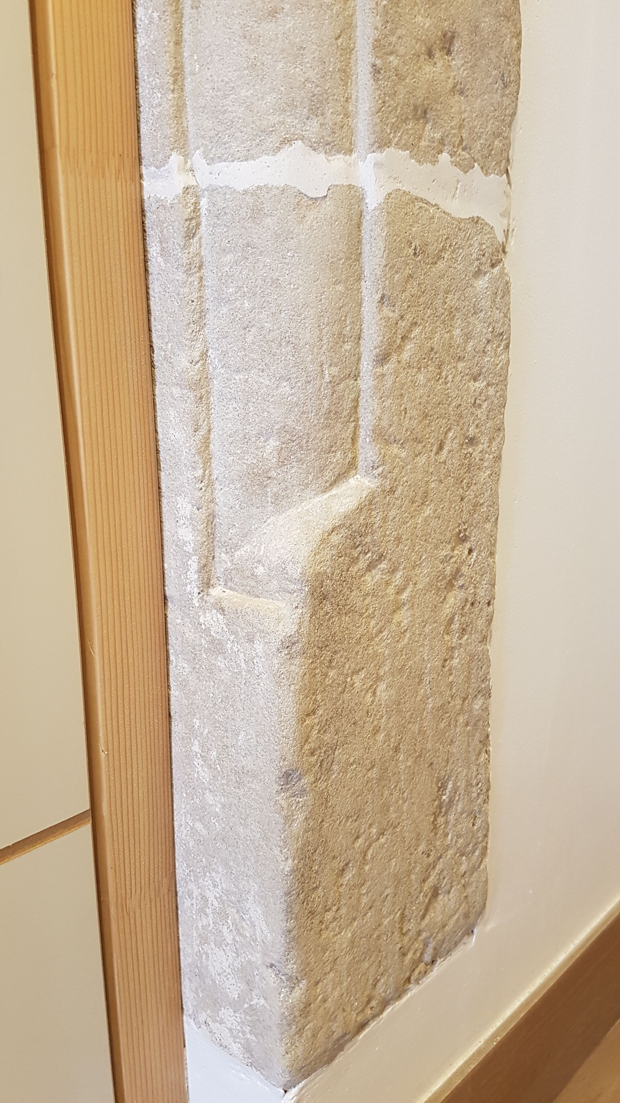 Een hoek van een kamer met een structuurwand en een houten deuropening.