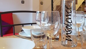 Una mesa de comedor con una botella de vino 'Merveille', varias copas de vino y un bol.