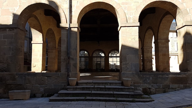 Un edificio de piedra con tres grandes arcos y una escalera que lleva a un espacio cubierto.