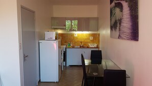 Eine kompakte Küchenzeile mit Kühlschrank, Mikrowelle und Spüle, sowie ein Essbereich mit Tisch und Stühlen.