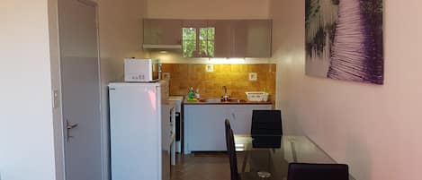 A compact kitchen with a refrigerator, microwave, sink, and a dining area with a table and chairs.