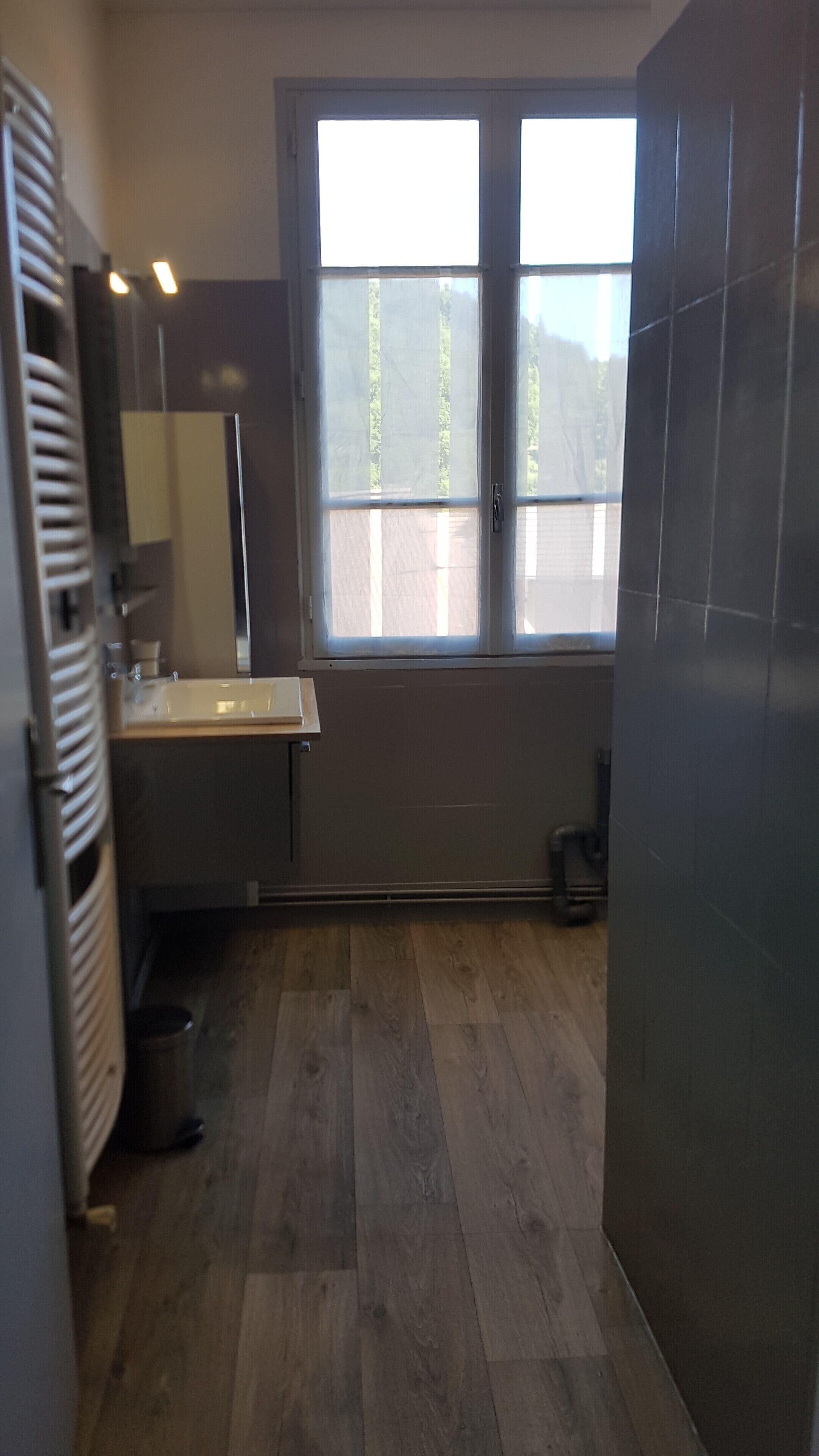A modern kitchen with a large window, a sink, and a trash bin.
