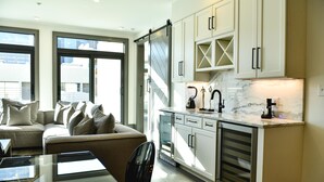 Une cuisine moderne avec des meubles blancs, un plan de travail en marbre et une porte coulissante.