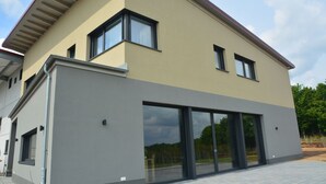 A modern two-story house with large sliding glass doors and a flat roof. - Weingut Bugner Meizelhof (Klein-Winternheim)