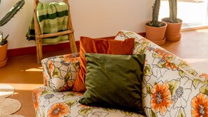 Un soggiorno con divano, cuscini, una scala e piante di cactus.