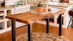 Una cucina con un tavolo di legno, lampade di vimini appese e uno schienale a parete decorato.