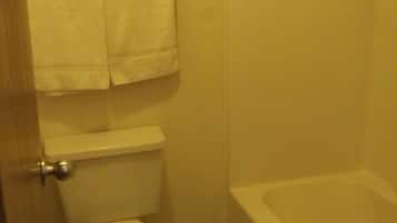 Een kleine badkamer met een toilet, een douche en een handdoekrek met twee handdoeken.