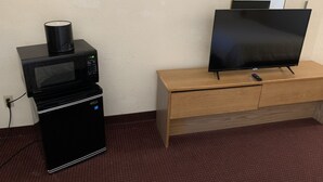 A compact kitchenette with a microwave, a small refrigerator, and a wooden cabinet with a flat-screen TV. - Plaza inn Lordsburg (Lordsburg)