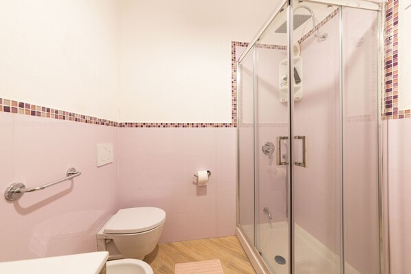 A bathroom with a glass-enclosed shower, a toilet, and a handrail. - The House on the Ischia Port (Ischia)