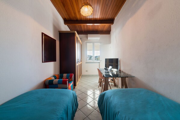A small, cozy room with two beds, a desk, and a window. - The House on the Ischia Port (Ischia)