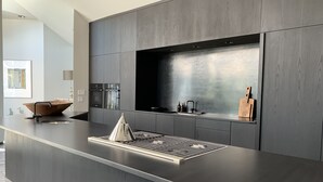 A modern kitchen with a large island, built-in appliances, and a sleek backsplash.