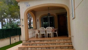 Ein Gebäude mit einer überdachten Terrassenfläche, komplett mit Tisch und Stühlen, einer Treppe zum Eingang und einem Schild mit der Aufschrift 'CASA COCOD'.