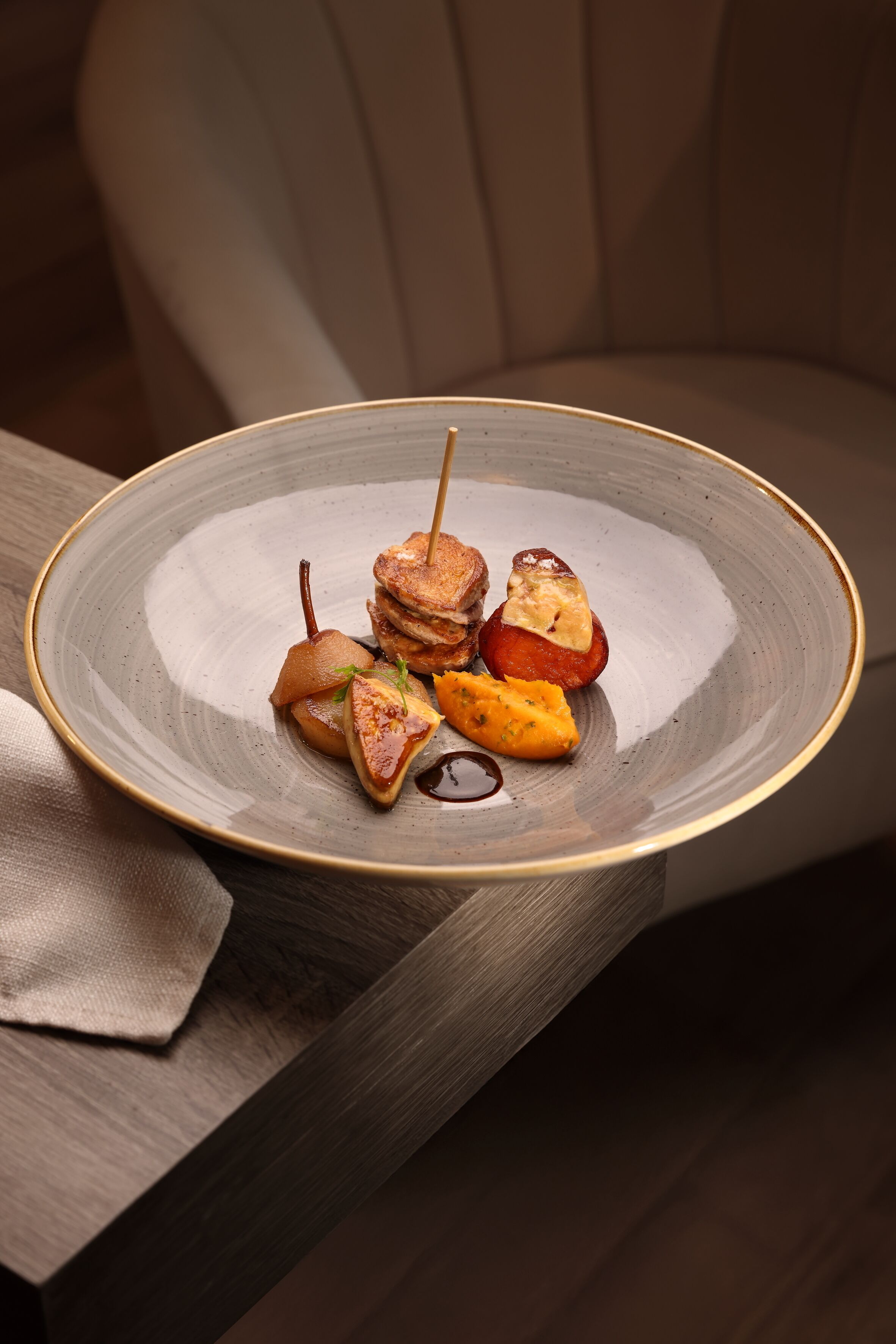 A plate of food with a toothpick, including what appears to be pancakes and a slice of fruit, on a table.