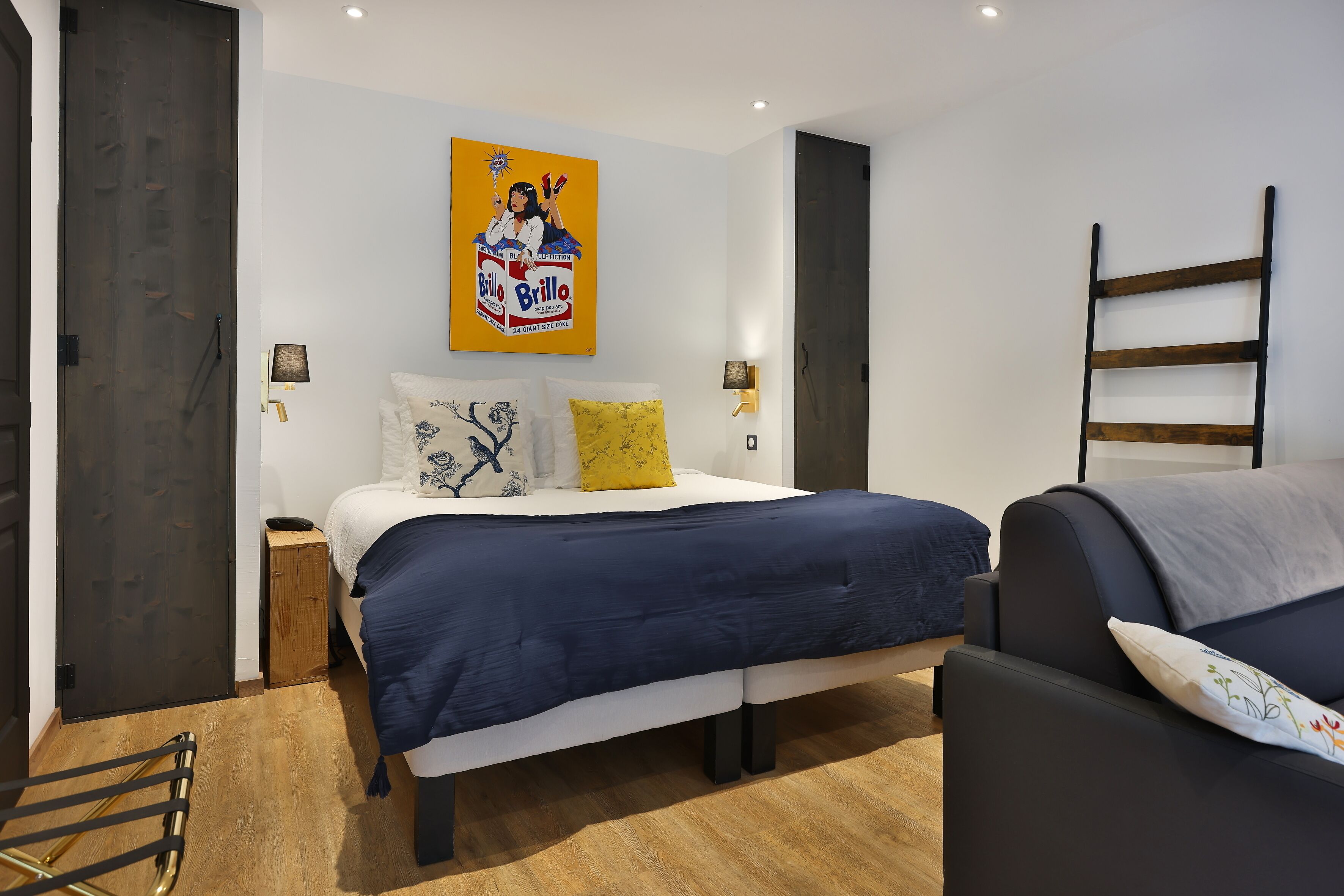 A modern bedroom with a bed, bedside lamps, a wooden floor, and a painting on the wall.