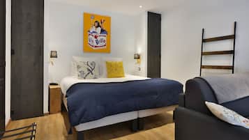 A modern bedroom with a bed, bedside lamps, a wooden floor, and a painting on the wall.