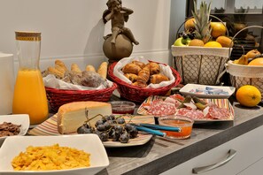 Ein reichhaltiges Frühstücksbuffet mit verschiedenen Speisen, darunter Brot, Käse, Obst und Wurstwaren.