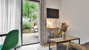 A modern room with a desk, chair, and a flat-screen TV mounted on the wall. - L'Atelier d'Epicure - Logis (Castels et Bézenac)
