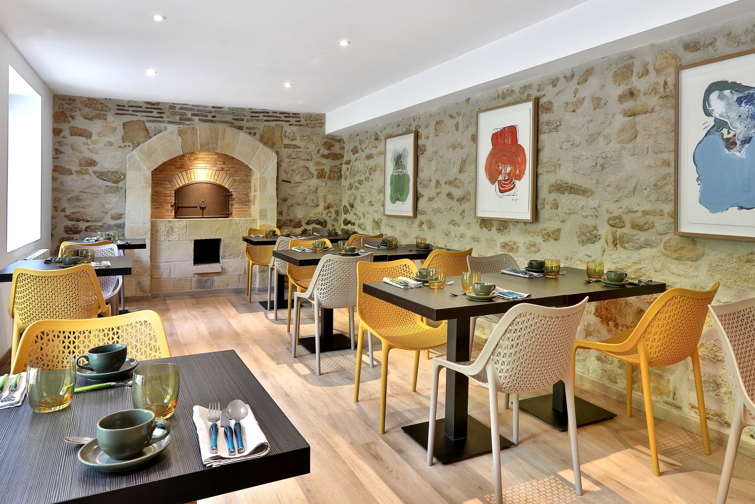 Un ristorante con pareti in pietra, tavoli in legno e sedie gialle.