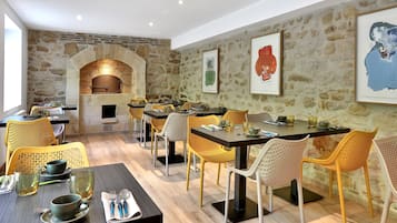 Un ristorante con pareti in pietra, tavoli in legno e sedie gialle.