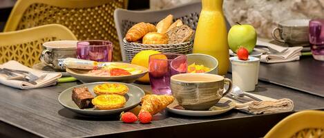 A breakfast setting with plates of food, a croissant, a glass of orange juice, and a bottle of milk.