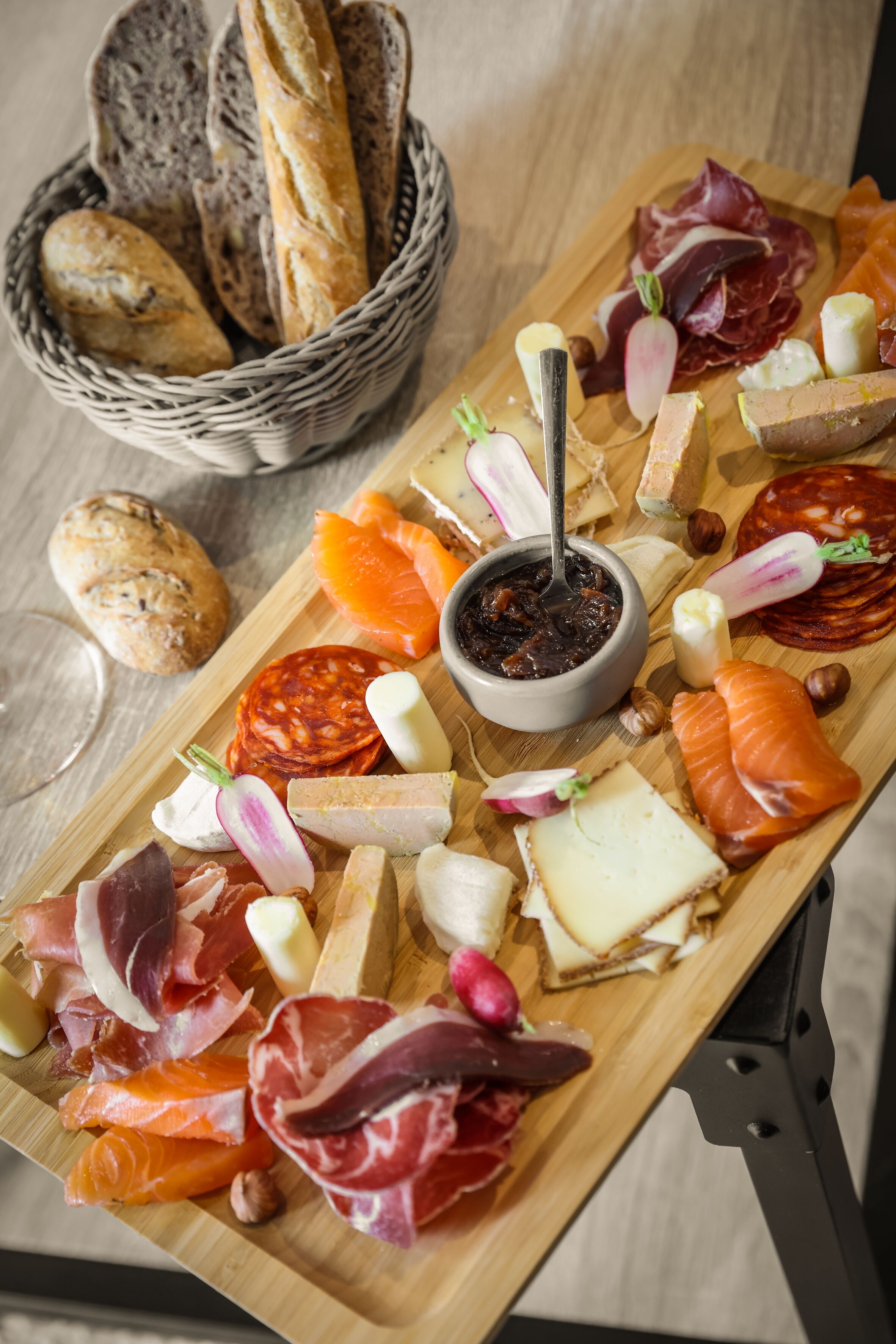 A charcuterie board with various meats, cheeses, and bread on a wooden table.
