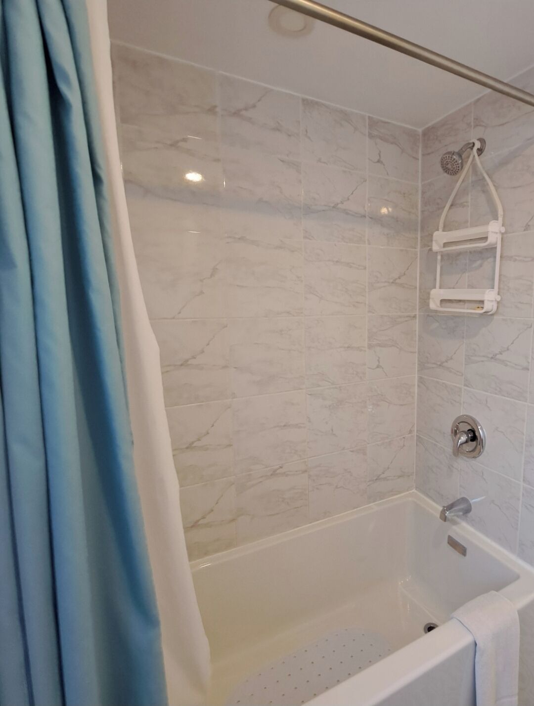Ein Badezimmer mit einer Badewanne, einer Dusche und einem Handtuchhalter.