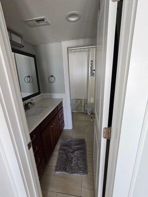 Un baño pequeño con lavamanos doble, espejo, inodoro y cortina de ducha.