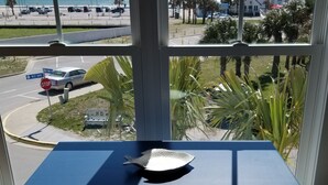 A view from a window with a stop sign and a car on the street, palm trees, and buildings in the background. - Ocean Views!102 West Terminal Blvd Unit #15 Atlantic Beach, NC (Atlantic Beach)