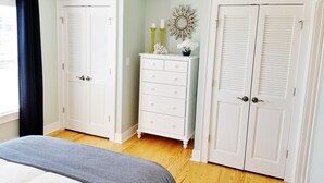 A bedroom with a bed, two white wardrobes, a dresser, a decorative mirror, and a window with a black curtain. - Ocean Views!102 West Terminal Blvd Unit #15 Atlantic Beach, NC (Atlantic Beach)