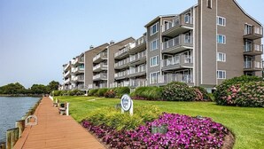 Um edifício residencial de vários andares com varandas, um calçadão de madeira e uma placa indicando uma associação de moradores.
