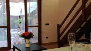A dining area with a table set for two, a vase with flowers, and a staircase. - villa 1 with garden in the green a few meters from the beach (Sabaudia)