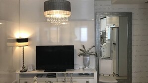 A modern living room with a flat-screen TV, a chandelier, and a minimalist design. - Apartamento Cadiz de Cine (Cádiz)