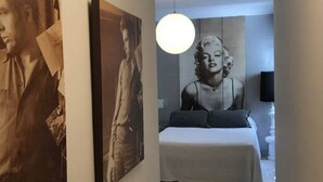 A bedroom with a bed, a wall-mounted light fixture, and two framed pictures. - Apartamento Cadiz de Cine (Cádiz)