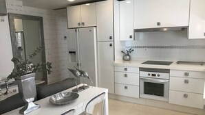 A modern kitchen with white cabinets, a stainless steel refrigerator, a built-in oven, and a sink. - Apartamento Cadiz de Cine (Cádiz)
