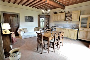 A rustic kitchen with wooden cabinets, a dining table, and a chandelier.