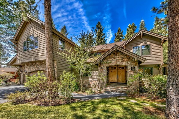A two-story house with a stone entrance and a wooden door.