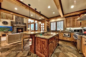 A spacious kitchen with a large island, wooden cabinetry, and a stone fireplace. - Hot Tub, Game Room, Near Heavenly Ski Resort. (South Lake Tahoe)