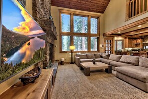 A cozy living room with a large flat-screen TV, a sectional sofa, and a stone fireplace. - Hot Tub, Game Room, Near Heavenly Ski Resort. (South Lake Tahoe)