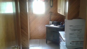 A small kitchen with wooden walls, a window with a white valance, a sink, and a refrigerator. - Lake front Rental!!!  (eagle lake)