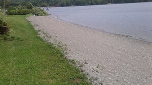 A gravel path leading to a lake with a grassy area on one side and a forested hill in the background. - Lake front Rental!!!  (eagle lake)