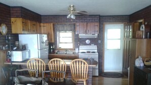 A kitchen with wooden cabinets, a refrigerator, a stove, and a dining area with a table and chairs. - Lake front Rental!!!  (eagle lake)