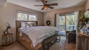 A bedroom with a bed, a bench, a desk, a ceiling fan, and a view of trees through the window. - Close to Prescott Square,2 Pools,Playground,Tennis,Pickle Ball,Trails,Wildlife (Prescott)